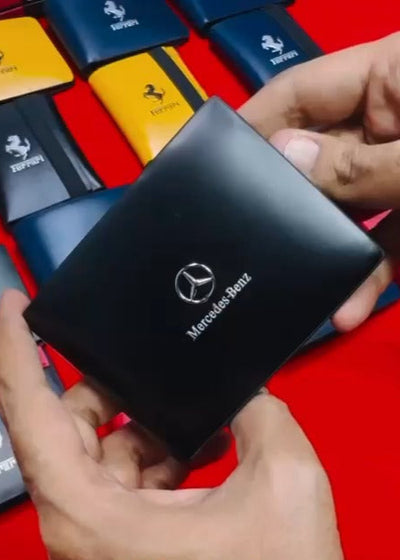 Black Mercedes-Benz wallet held by hands with colorful wallets in the background